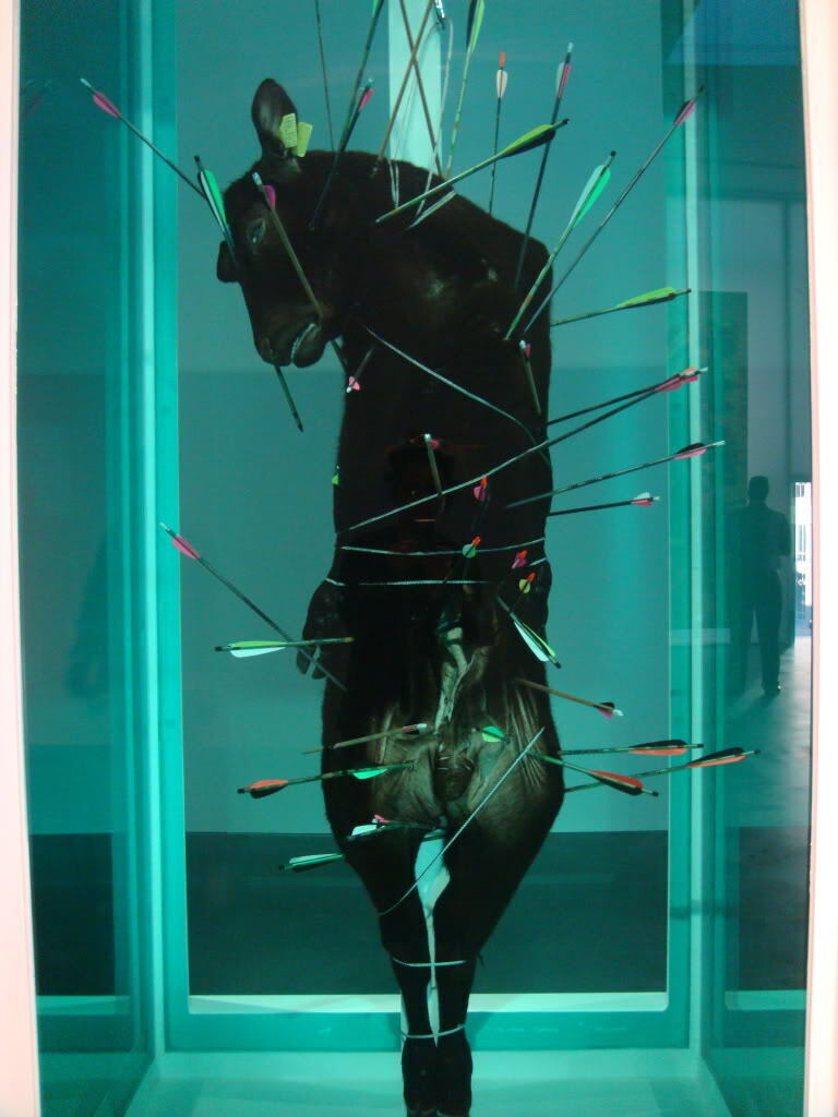 Damien Hirst. Saint Sebastian, Exquisite Pain. 2007. Glass, painted stainless steel, silicone, arrows, crossbow bolts, stainless steel cable and clamps, stainless steel carabiner, bullock and formaldehyde solution. 126.6 x 61.3 x 61.3 cm. The Goss-Michael Foundation, Dallas